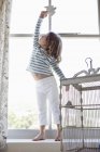 Niedliches kleines Mädchen spielt mit Spielzeugvogel am Fenster — Stockfoto