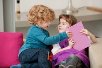 Boy sitting on a couch with his sister — Stock Photo