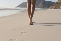 Крупным планом женских ног, идущих по песчаному пляжу — стоковое фото
