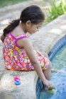 Kleines Mädchen spielt mit Gummi-Enten am Schwimmbadrand — Stockfoto