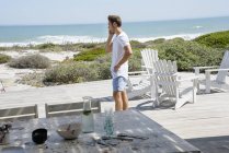 Молодий чоловік розмовляє по мобільному телефону на терасі на морському узбережжі — стокове фото