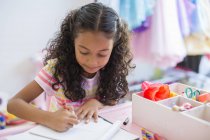 Концентрований маленька дівчинка, робити домашнє завдання на стіл — стокове фото