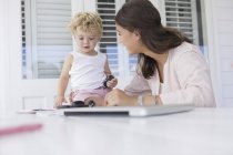 Mother playing with son at desk at home — Stock Photo