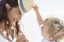 Baby boy playing with mother hat on beach — Stock Photo