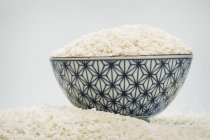 Ciotola di riso circondata da riso, fuoco selettivo — Foto stock