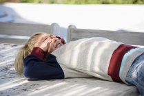 Playful boy lying on table outdoors with hands covering eyes — Stock Photo