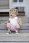 Carino bambino seduto su gradini con giocattolo — Foto stock