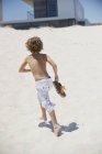 Shirtless boy running on sunny sandy beach — Stock Photo