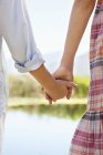 Close-up of kids holding hands at lake in nature — Stock Photo
