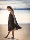 Jovem sonhadora em vestido andando na praia — Fotografia de Stock