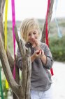 Mädchen lehnt mit bunten Bändern an Baum und isst Obst — Stockfoto