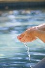 Close-up of male hands cupped with water of swimming pool — Stock Photo