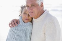 Primer plano de la pareja de ancianos reflexivo abrazo en la playa - foto de stock