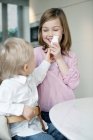 Menina sorrindo com irmão segurando garrafa de leite — Fotografia de Stock