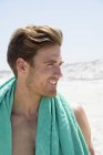 Feliz joven con toalla en los hombros disfrutando de la playa - foto de stock