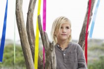 Menina loira pensativa em pé perto da árvore decorada com fitas — Fotografia de Stock