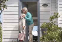 Старший чоловік вітає жінку біля дверей — стокове фото