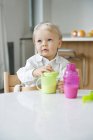Cute baby boy sitting at dining table in kitchen — Stock Photo