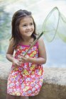 Маленькая девочка сидит у бассейна с сеткой в руках — стоковое фото