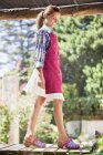 Menina sorridente no avental andando no cais no jardim ensolarado — Fotografia de Stock