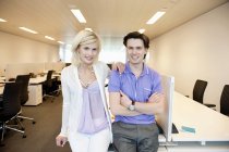 Portrait of smiling business couple leaning on desk in office — Stock Photo