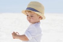 Крупним планом милий хлопчик в солом'яному капелюсі грає на пляжі — стокове фото