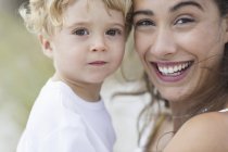Portrait de femme heureuse portant fils mignon à l'extérieur — Photo de stock