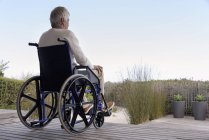 Старший чоловік в інвалідному візку розслабляється на відкритому повітрі — стокове фото