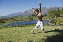 Bonito menino fazendo cartwheel contra na grama na natureza contra montanhas — Fotografia de Stock
