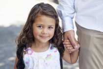 Портрет маленької дівчинки, що тримає батькову руку і дивиться на камеру — стокове фото