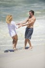 Couple ludique s'amuser sur la plage de sable fin — Photo de stock