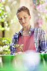 Вдумчивая девушка в фартуке садоводства на открытом воздухе — стоковое фото