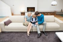 Родители сидят на диване со своим сыном — стоковое фото