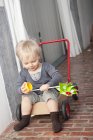 Веселий маленький хлопчик грає з коліщатком на візку — стокове фото