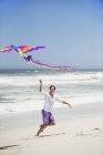Homme s'amuser avec cerf-volant volant sur la plage — Photo de stock