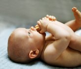 8 meses menino deitado e brincando com os pés — Fotografia de Stock