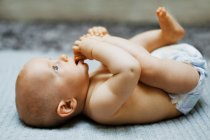 8 meses menino deitado e brincando com os pés — Fotografia de Stock
