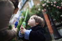 Little boy and his mother blowing bubbles in the street — Stock Photo