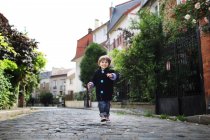 Kleiner Junge läuft in einer gepflasterten engen Straße — Stockfoto