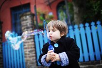 Petit garçon soufflant des bulles dans la rue — Photo de stock