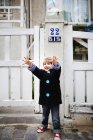 Маленький хлопчик з простягнутими руками намагається зловити бульбашки на вулиці — стокове фото