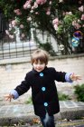 Petit garçon soufflant des bulles dans la rue — Photo de stock
