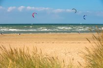 Francia, Normandía, gente disfrutando de una tarde ventosa en la playa, kitesurf - foto de stock