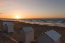 Francia, Normandía, cabañas de playa en la playa al atardecer - foto de stock