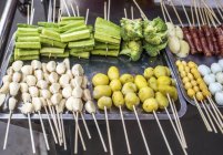 Brochetas de verduras en el mercado callejero en el distrito chino - foto de stock