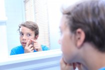 France, jeune garçon dans la salle de bain regardant dans le miroir. — Photo de stock
