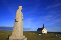 Islandia, Sudurland. Strandarkirkja, Selvogur. Pequeña iglesia y estatua en el campo - foto de stock