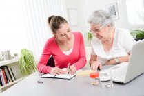 Giovane donna allegra aiutare la donna anziana con pillole prescrizione medica — Foto stock