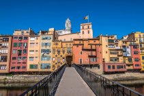 Spanien Katalonien, Girona, Fluss Onyar, Fußgängerbrücke Sant Agusti, farbige Fassaden der Altstadt und Glockenturm der Kathedrale von Girona — Stockfoto