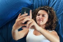 Menina adolescente e vida cotidiana. Na cama com smartphone — Fotografia de Stock